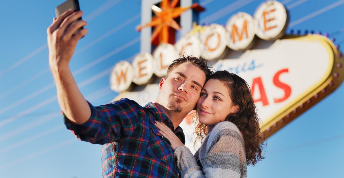 Couple taking a selfie in front of the Welcome to Fabulous Las Vegas sign
